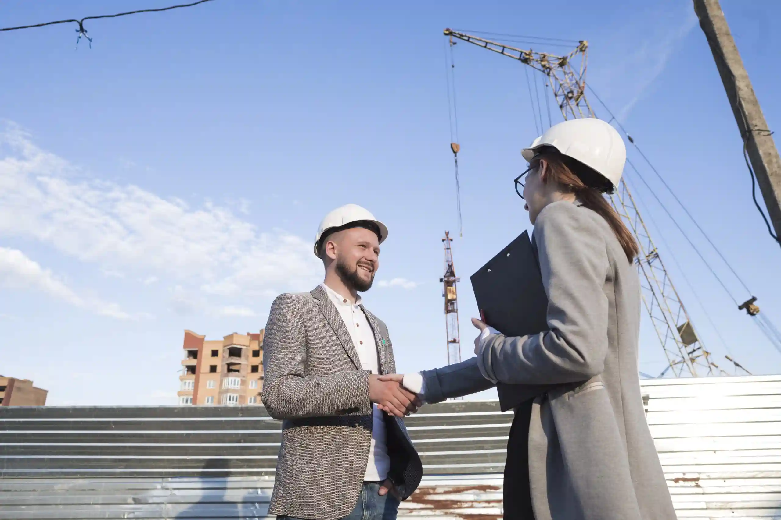 smiling-engineers-shaking-hands-construction-site-architectural-project-scaled